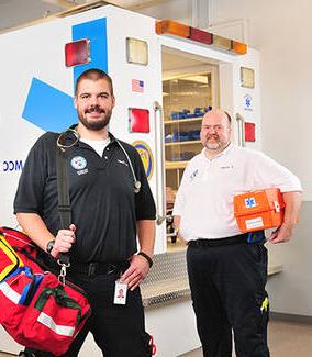 罗切斯特公共安全培训中心，两名MCC EMS男学生站在救护车模拟器前, NY.